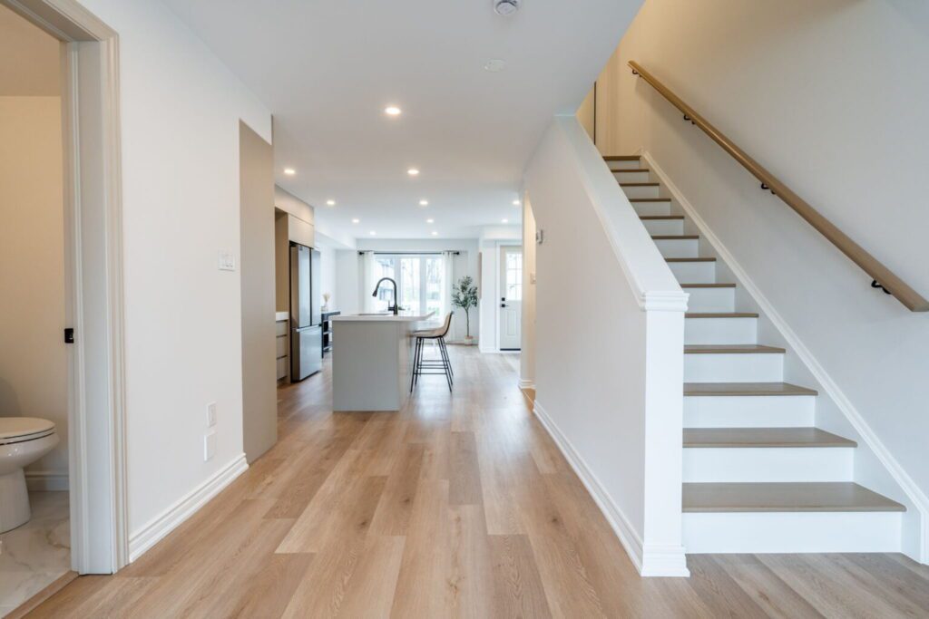 Bright modern hallway with wooden floors and white staircase.