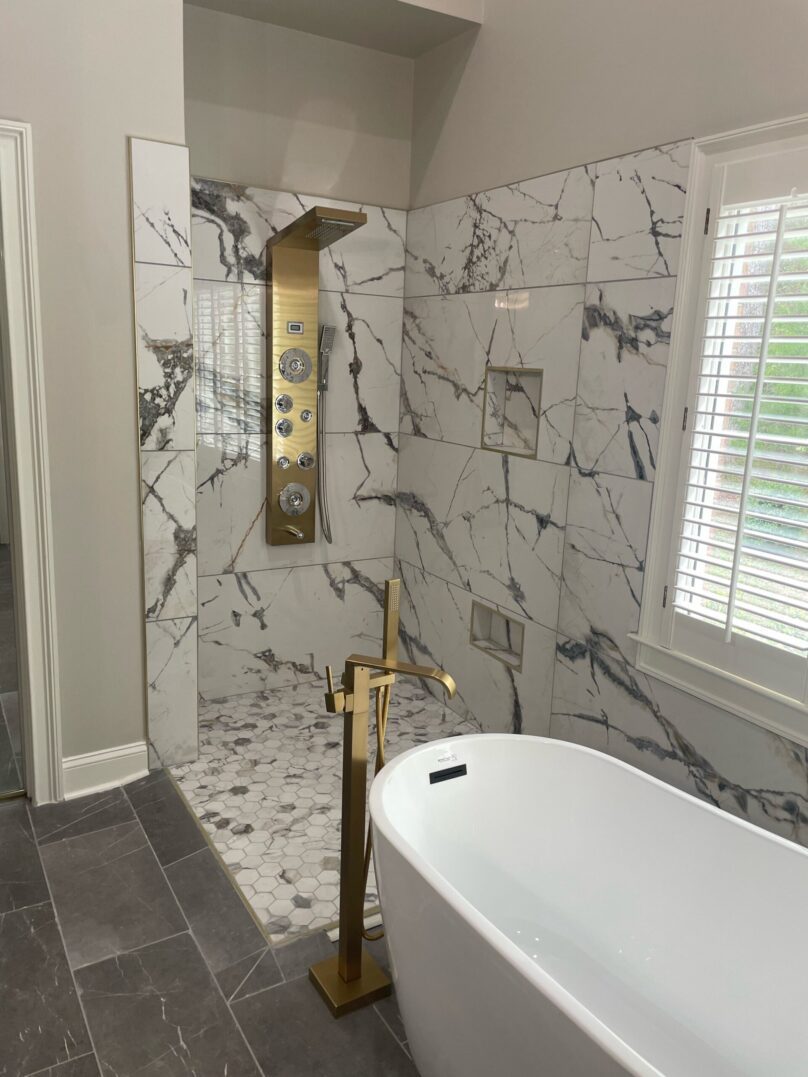 Elegant bathroom with marble shower and freestanding bathtub.