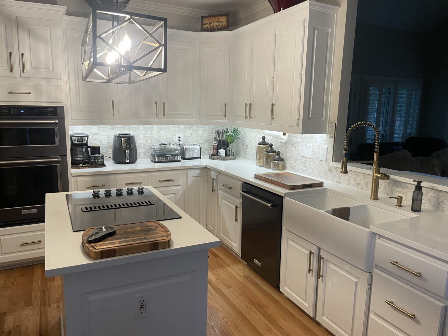 Modern white kitchen with stainless steel appliances and wooden floors.