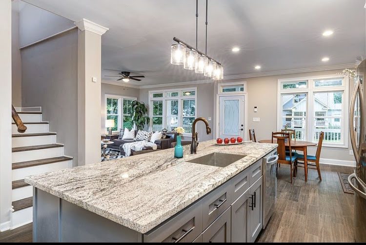Modern kitchen with granite island and open living area.