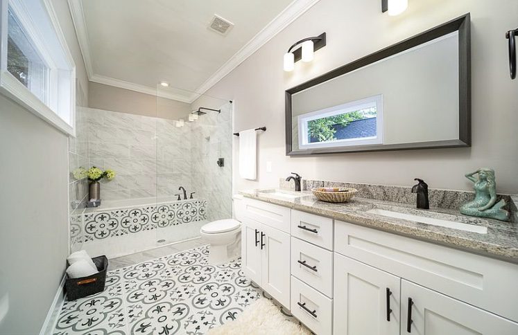 Bright bathroom with patterned tile floor and large vanity mirror.