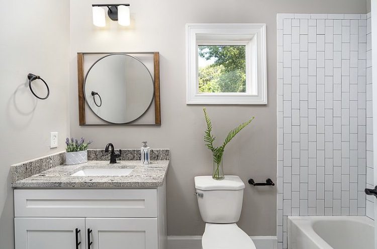 Clean bathroom with round mirror and white decor.