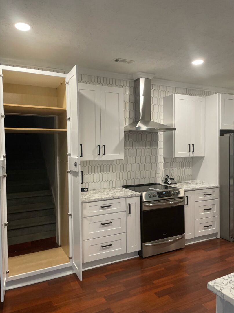 Modern white kitchen with stainless steel appliances and spacious pantry.