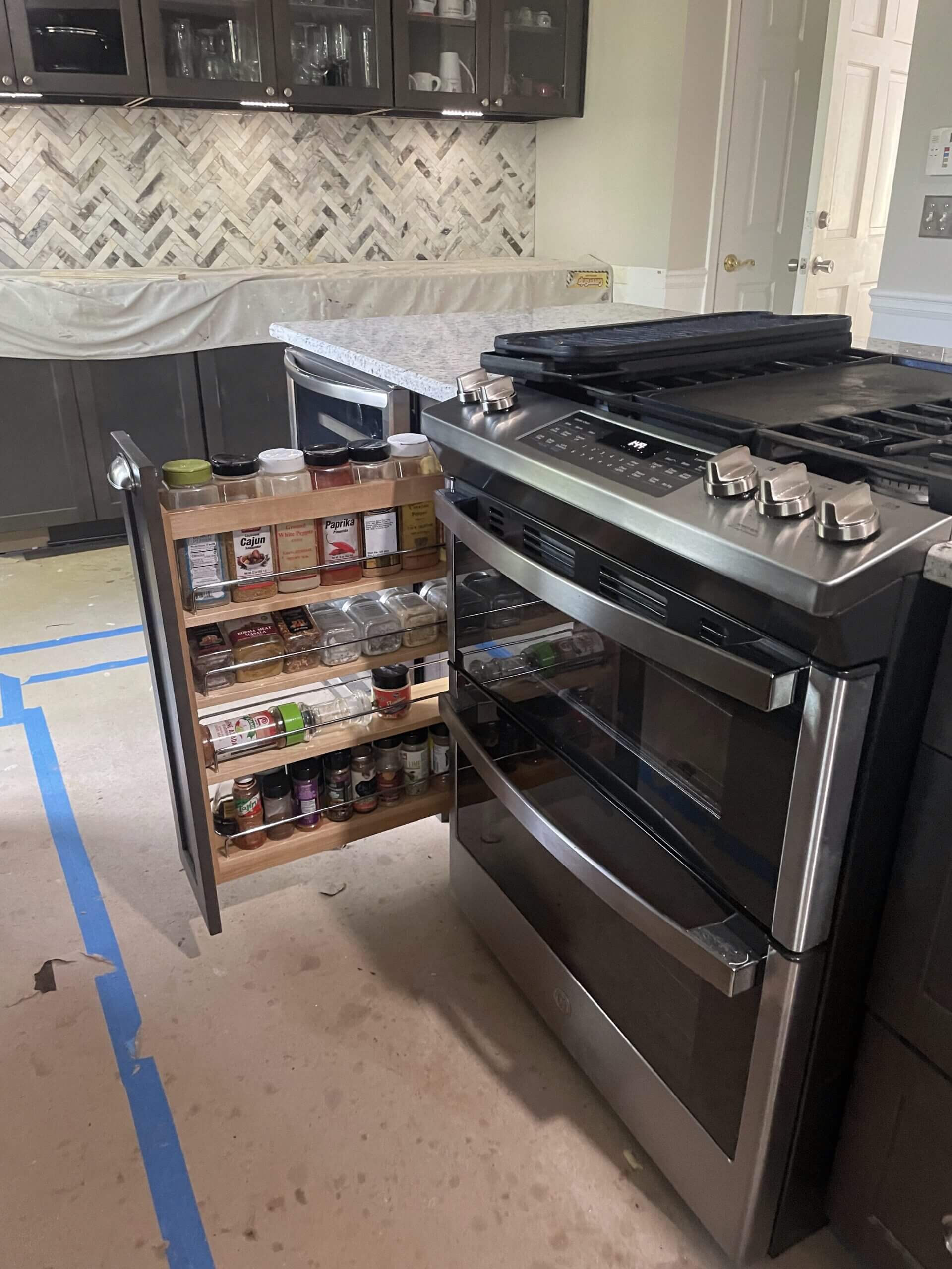 A kitchen stove next to a spice rack with various seasonings.