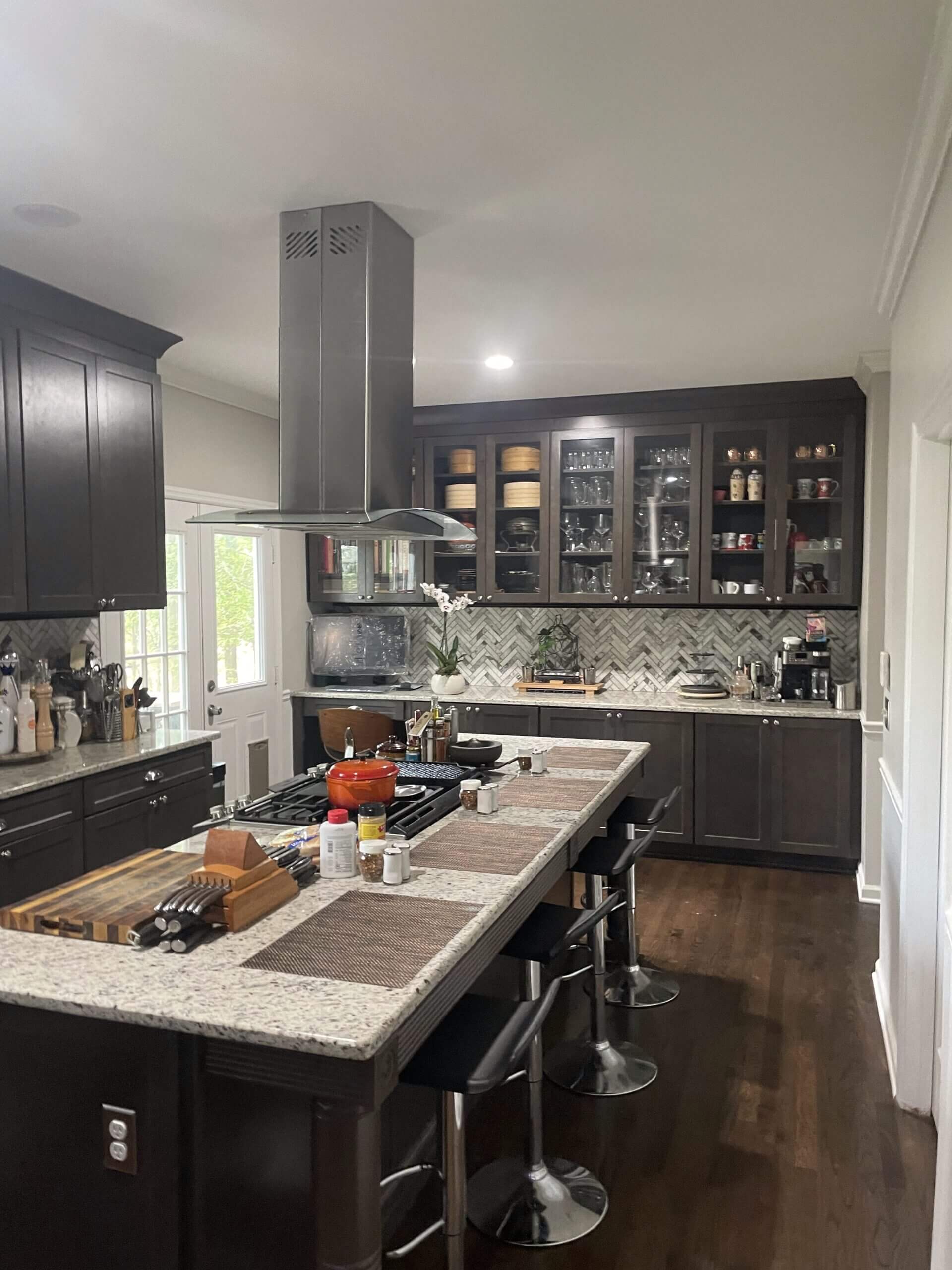 Modern kitchen with dark cabinets, a large island, and stainless steel appliances.