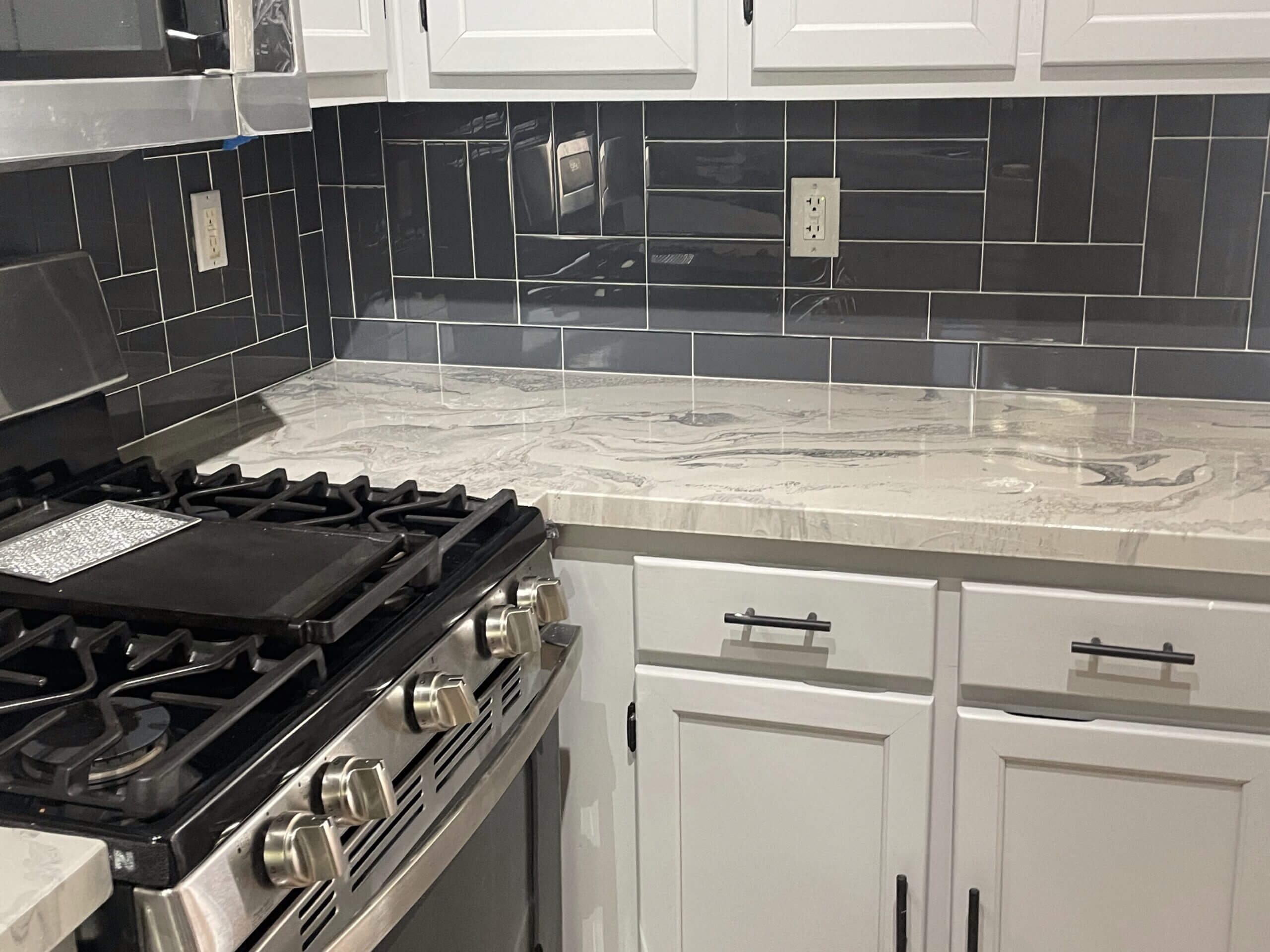 Modern kitchen with stainless steel stove and marble countertop.