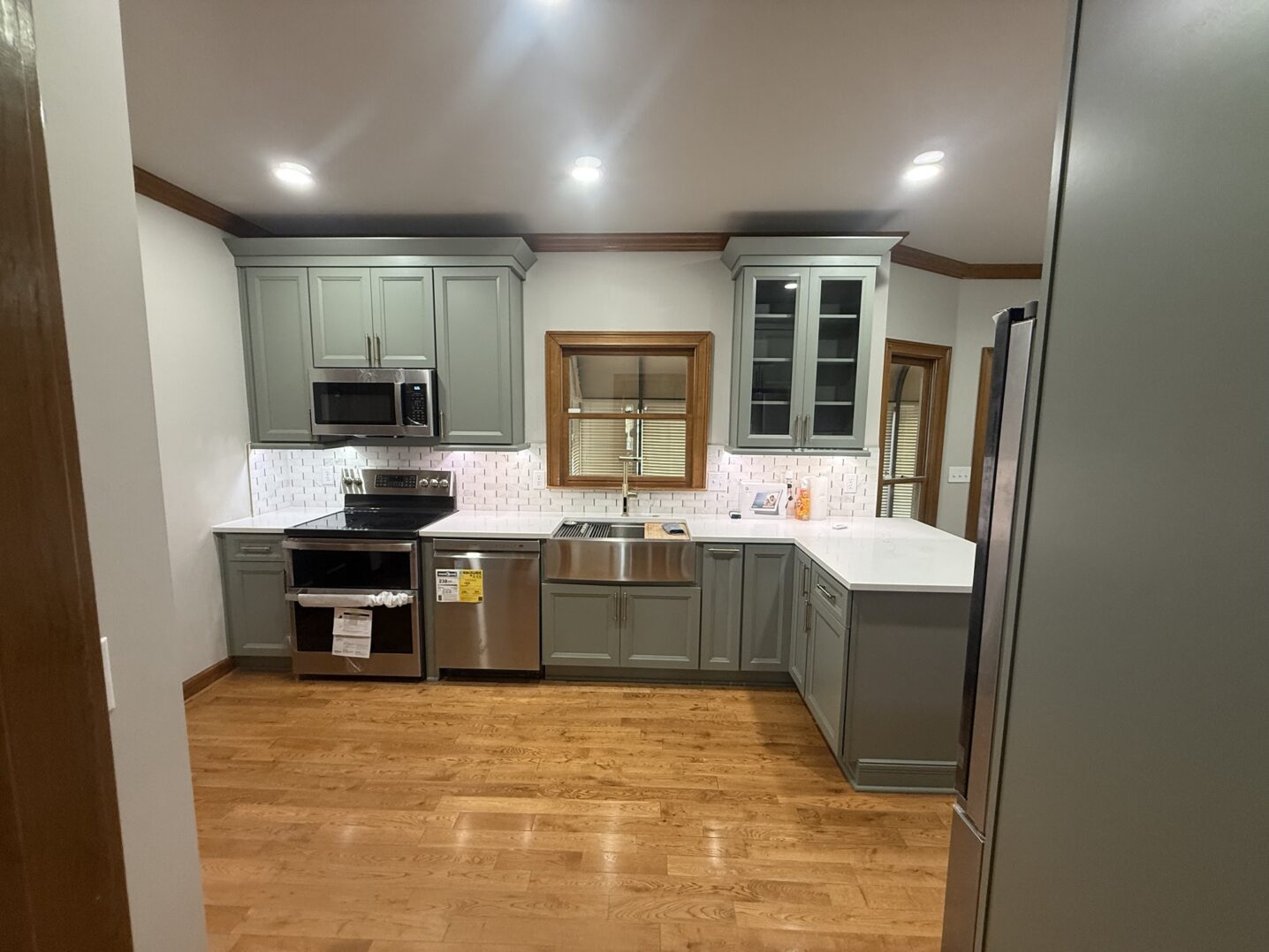 Modern kitchen with gray cabinets, stainless steel appliances, and wooden floors.