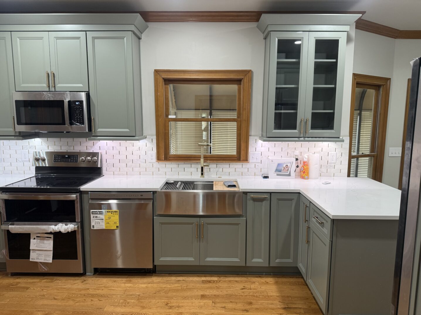 Modern kitchen with gray cabinets, farmhouse sink, and stainless steel appliances.