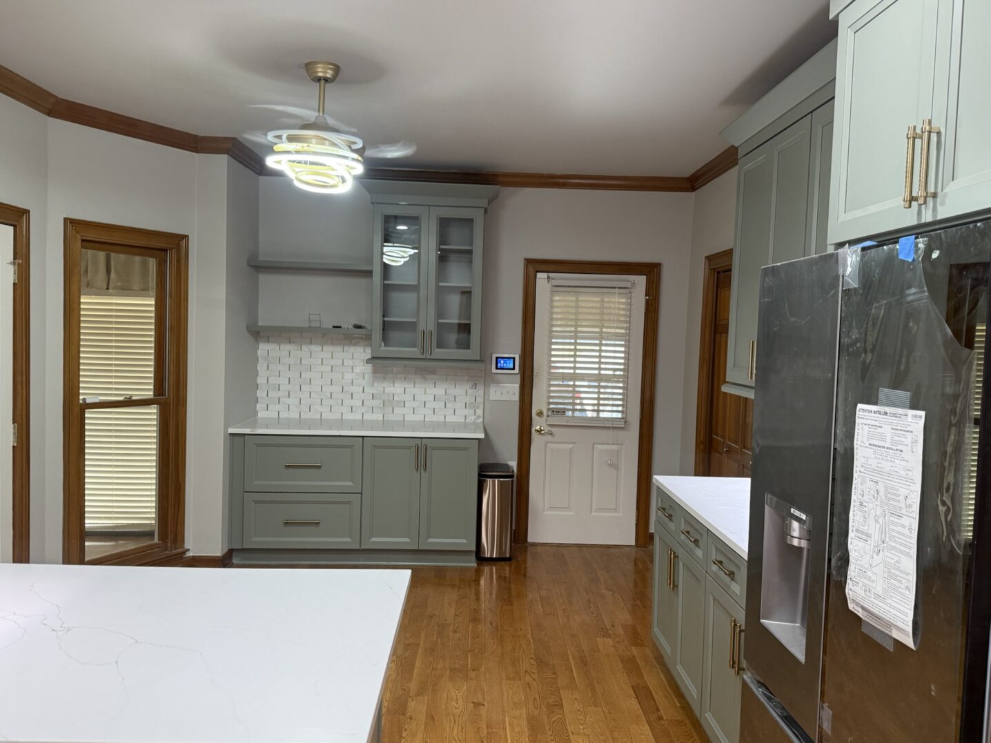 A modern kitchen with gray cabinets and wooden flooring.