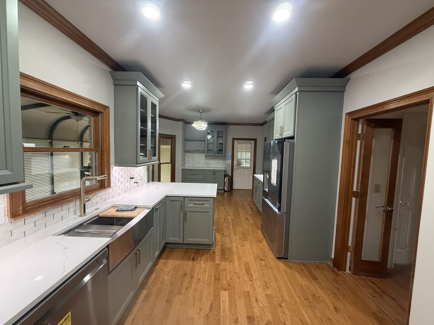Modern kitchen with gray cabinets and wooden flooring.