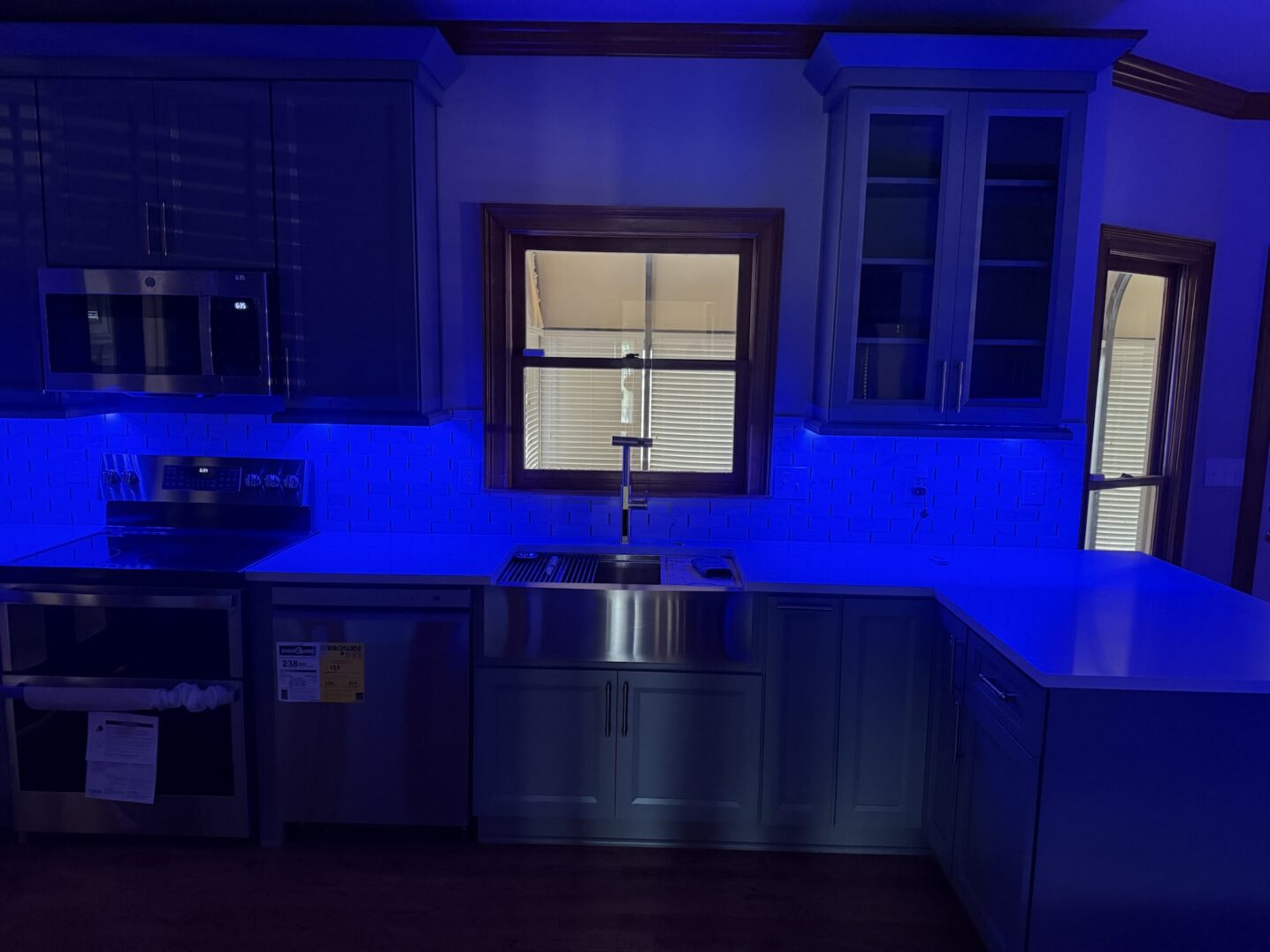 Modern kitchen with blue LED lighting and stainless steel appliances.