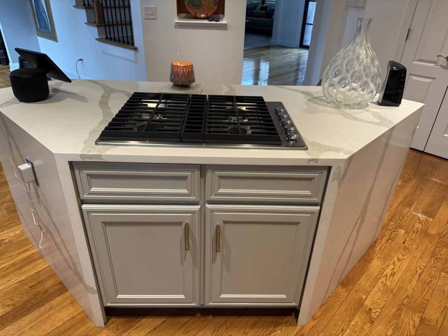 Kitchen island with built-in gas cooktop and white cabinetry.